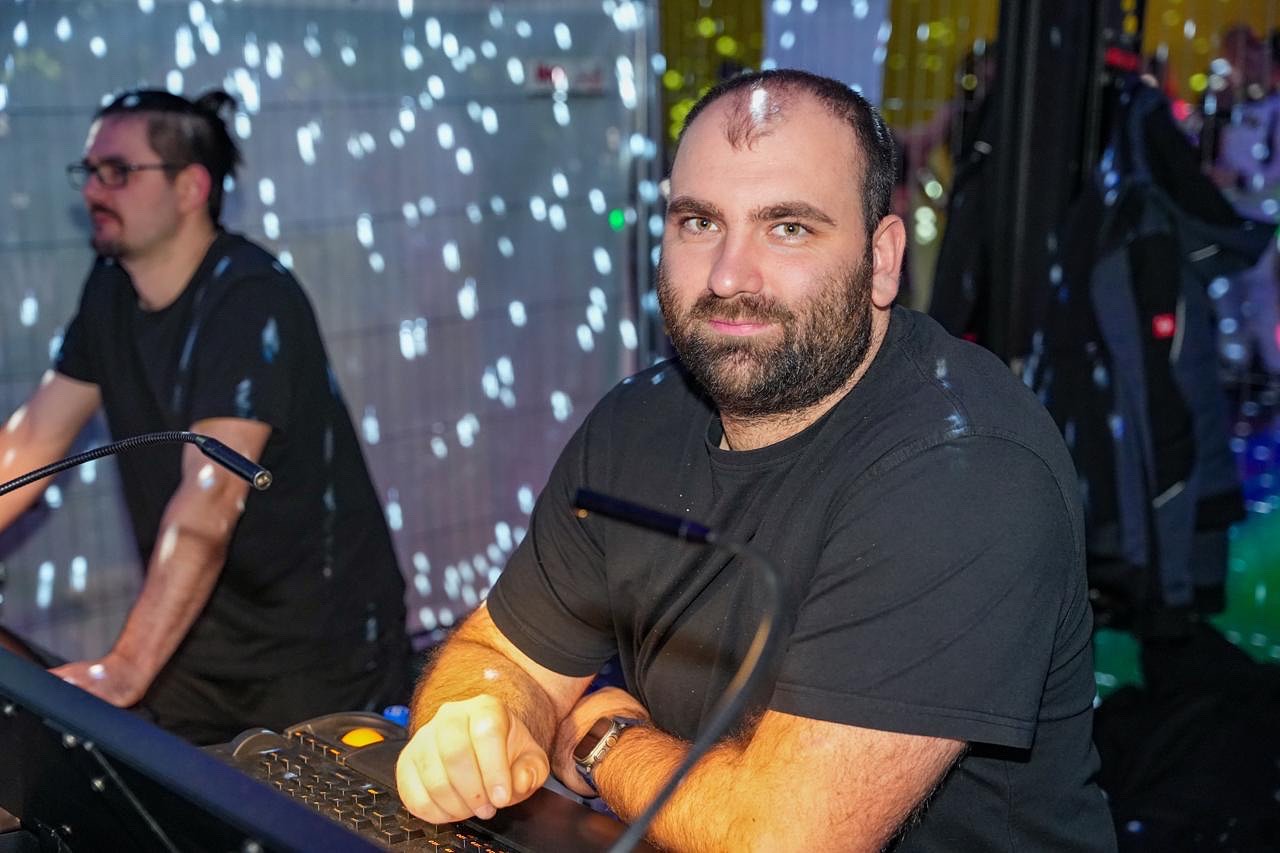 Tobias Krüger sitzt während einer Veranstaltung am Lichtpult, im Hintergrund ein LED-Sternenvorhang und ein zweiter Techniker