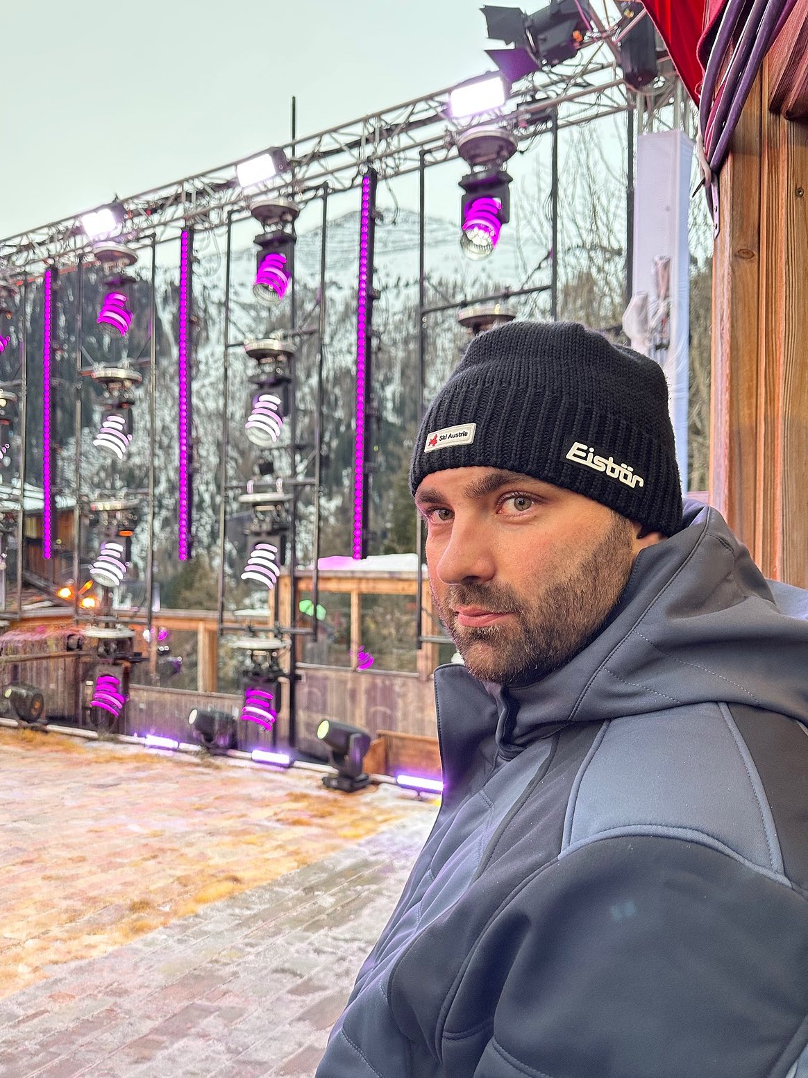 Tobias Krüger vor einer Bühnentraverse mit magentafarben leuchtenden Scheinwerfern bei einer Winterveranstaltung im Freien