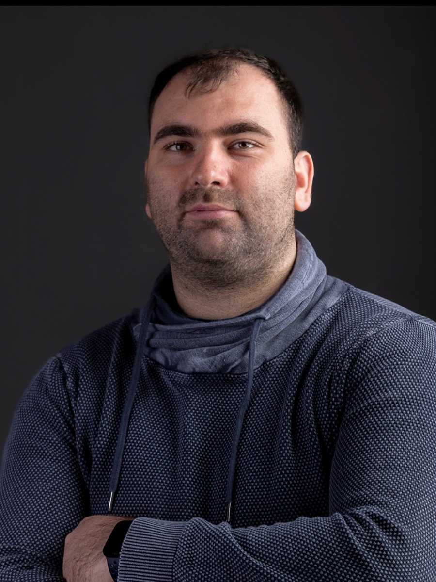 Porträt von Tobias Krüger, Meister für Veranstaltungstechnik, mit verschränkten Armen vor dunklem Hintergrund